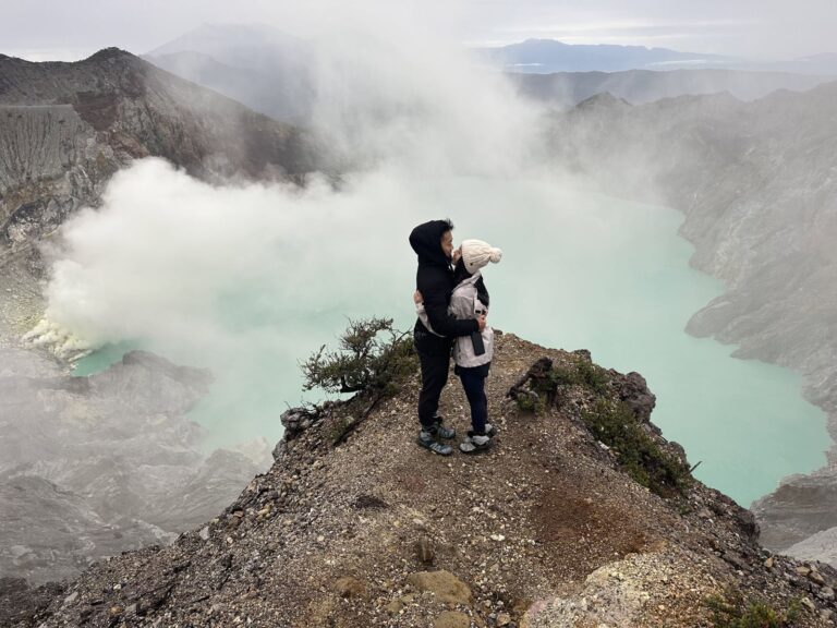 A guest on the Ijen crater rim with sulfur smoke over the lake