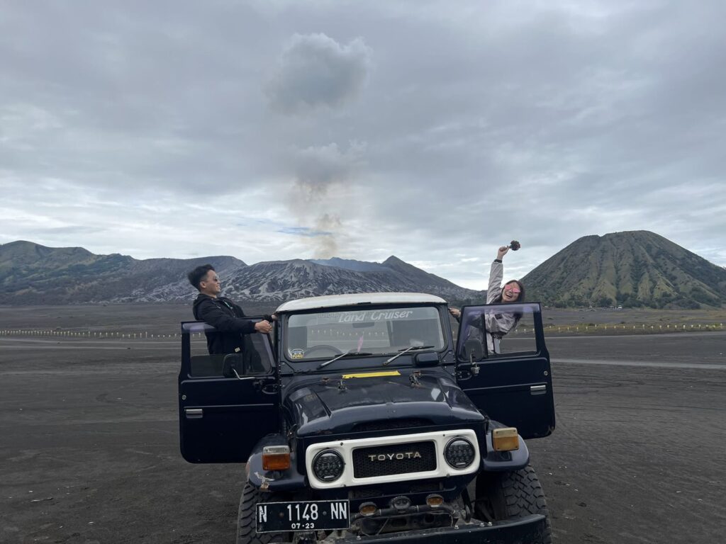 Guests with a 4x4 jeep on the Sea of Sand, Mount Bromo behind