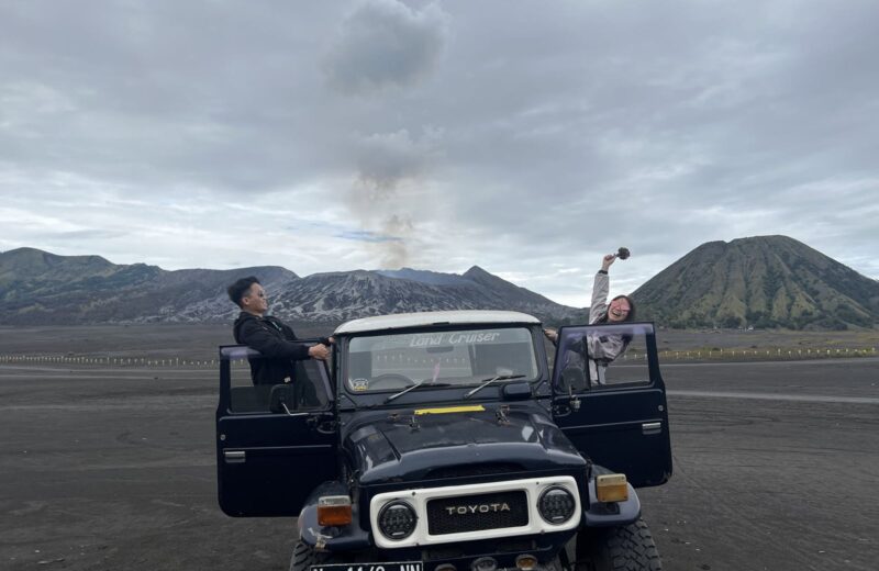 Guests with a 4x4 jeep on the Sea of Sand, Mount Bromo behind