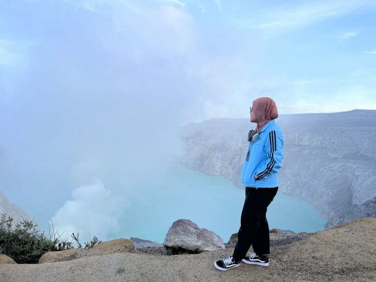 A guest beside the turquoise Ijen crater lake and sulfur smoke