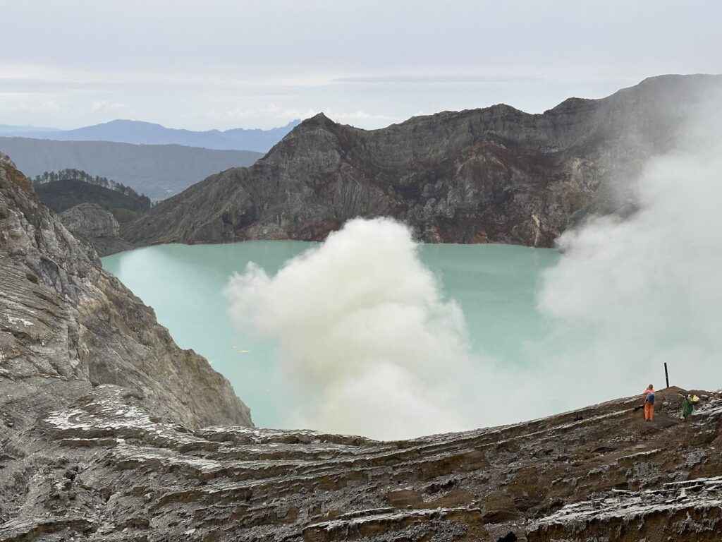 Turquoise crater lake of Kawah Ijen with sulfur smoke