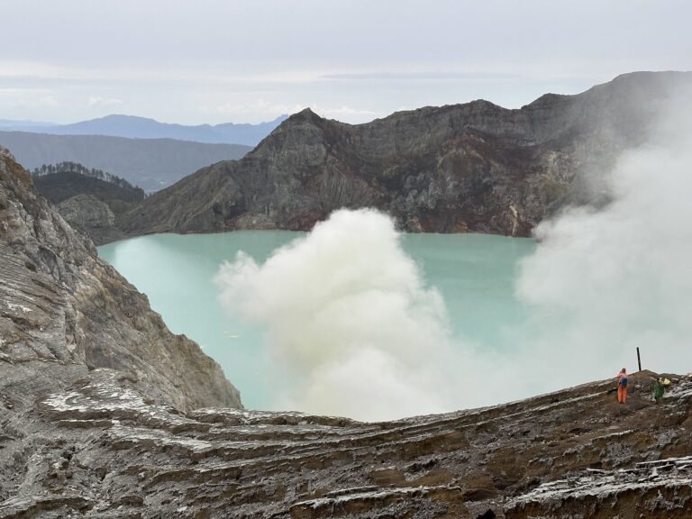 Turquoise crater lake of Kawah Ijen with sulfur smoke
